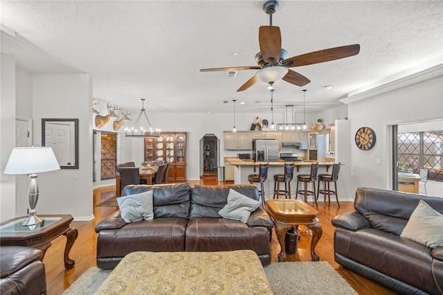 living room featuring a textured ceiling, ceiling fan with notable chandelier, and light hardwood / wood-style flooring