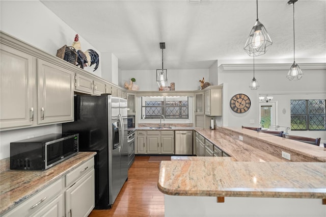 kitchen featuring pendant lighting, light hardwood / wood-style floors, appliances with stainless steel finishes, and sink