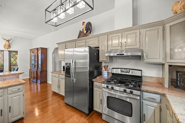 kitchen with appliances with stainless steel finishes, gray cabinetry, light stone counters, and light wood-type flooring