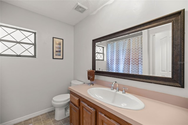 bathroom with toilet, tile flooring, plenty of natural light, and vanity