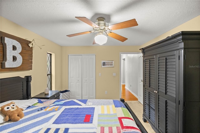 carpeted bedroom with a closet, ceiling fan, and a textured ceiling