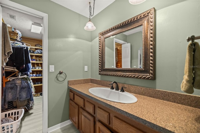 bathroom with a textured ceiling, vanity with extensive cabinet space, and hardwood / wood-style flooring