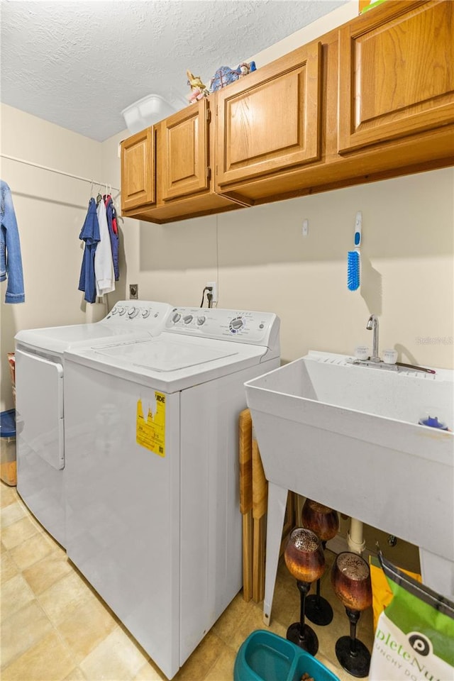 laundry room featuring cabinets, a textured ceiling, washer and dryer, and light tile flooring