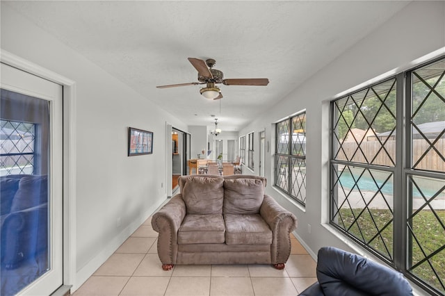 living room featuring a healthy amount of sunlight, light tile floors, and ceiling fan with notable chandelier