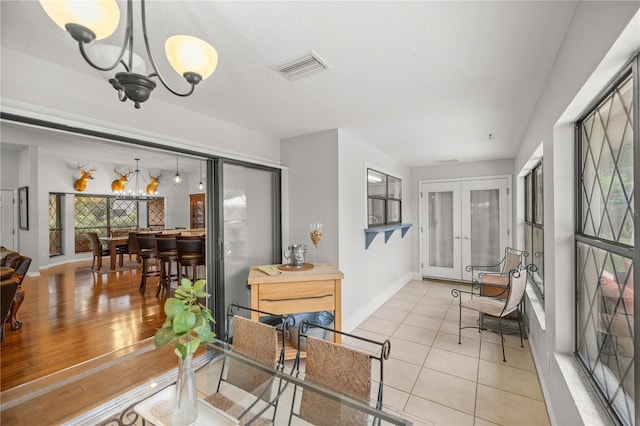 interior space featuring french doors, an inviting chandelier, and light hardwood / wood-style floors