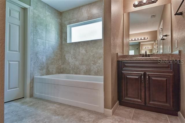 bathroom with tiled shower / bath combo, vanity, and tile floors