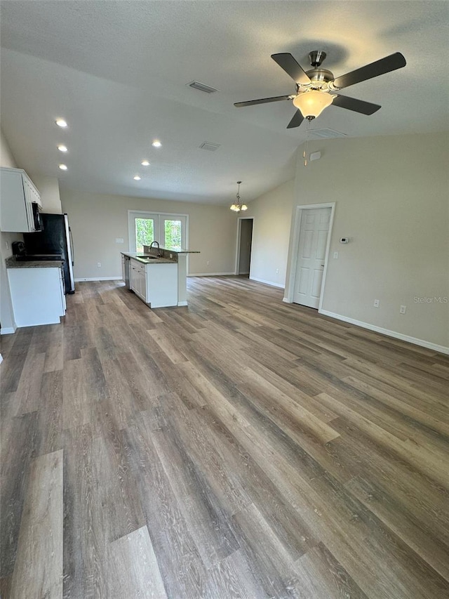 unfurnished living room featuring lofted ceiling, sink, a textured ceiling, ceiling fan, and hardwood / wood-style floors