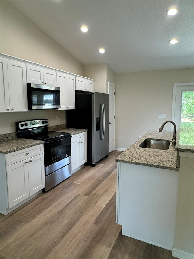 kitchen featuring white cabinetry, appliances with stainless steel finishes, sink, and light stone counters