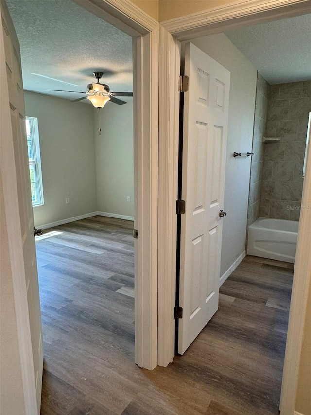 hallway with hardwood / wood-style floors and a textured ceiling