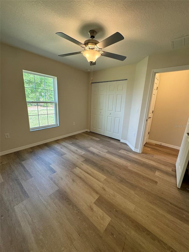 unfurnished bedroom with ceiling fan, light hardwood / wood-style flooring, a closet, and a textured ceiling