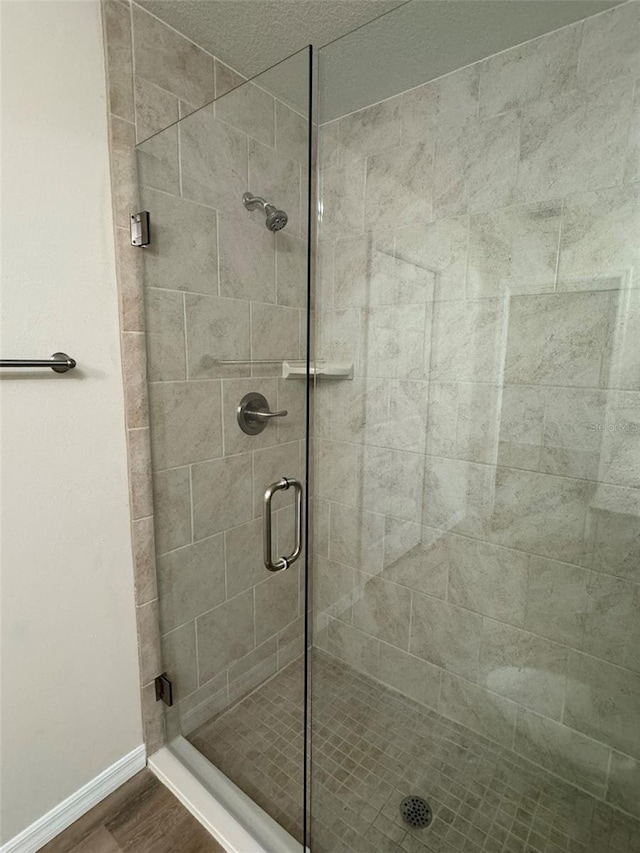 bathroom with a shower with door and hardwood / wood-style floors