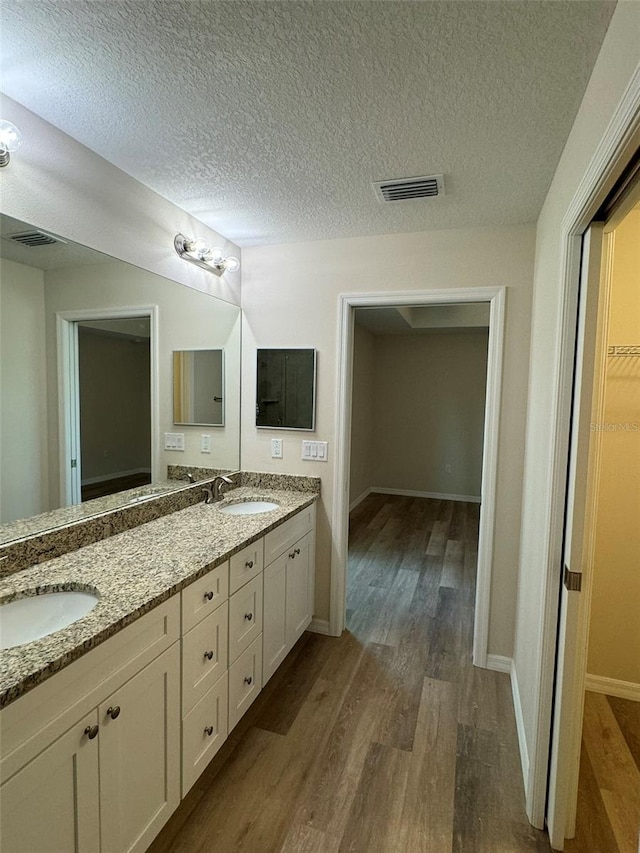 bathroom with vanity, hardwood / wood-style floors, and a textured ceiling