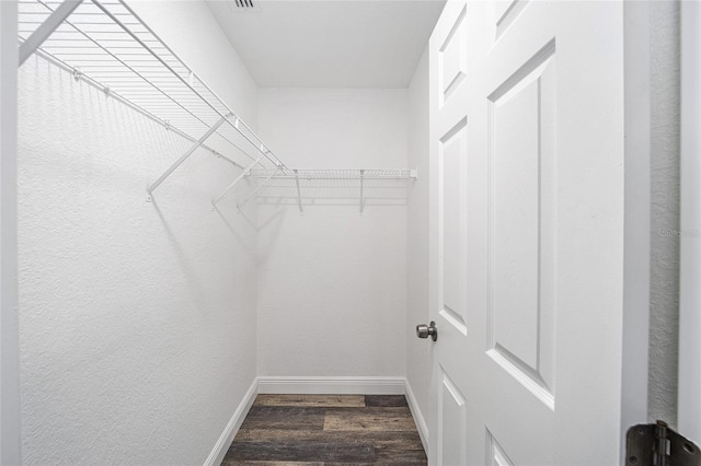 walk in closet with dark wood-type flooring