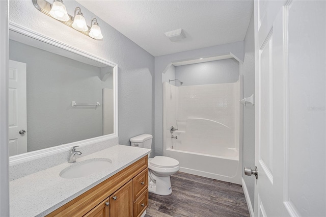 full bathroom with vanity, hardwood / wood-style flooring, toilet, a textured ceiling, and shower / bath combination