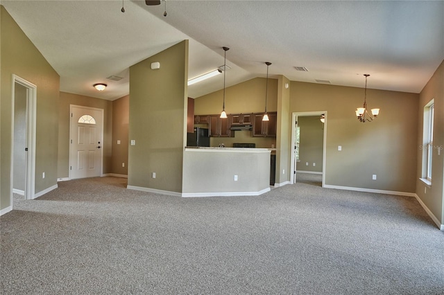 unfurnished living room featuring vaulted ceiling, ceiling fan with notable chandelier, and carpet floors