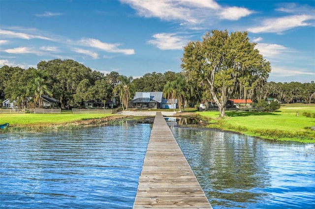 view of dock featuring a lawn and a water view