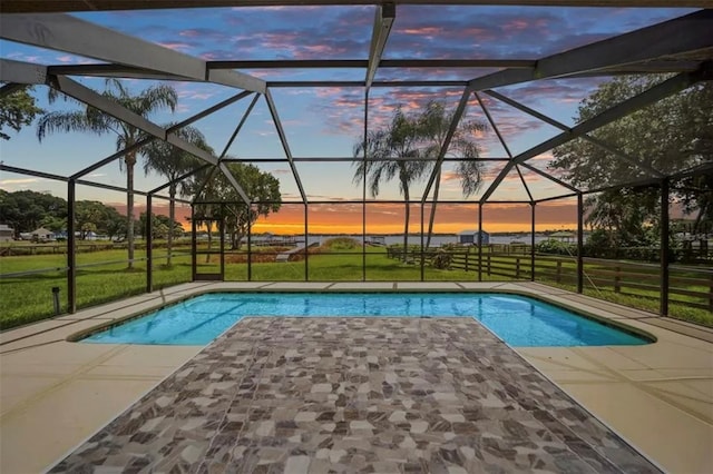 pool at dusk with a lanai, a patio area, and a yard