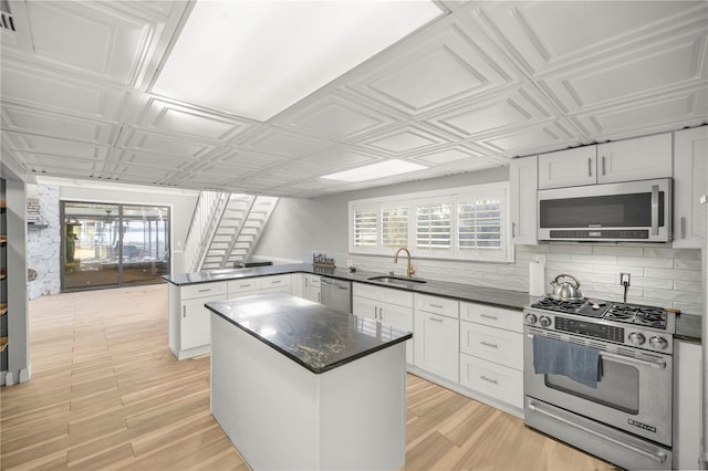 kitchen featuring sink, white cabinets, a kitchen island, stainless steel appliances, and a healthy amount of sunlight