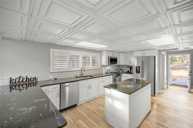 kitchen featuring light wood-type flooring, a center island, sink, white cabinetry, and stainless steel appliances