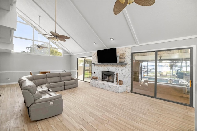 living room with light wood-type flooring, a stone fireplace, beam ceiling, and ceiling fan