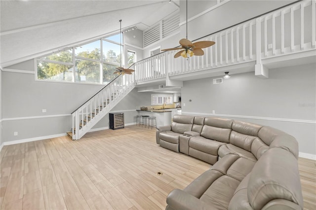 living room with ceiling fan, hardwood / wood-style flooring, and a high ceiling