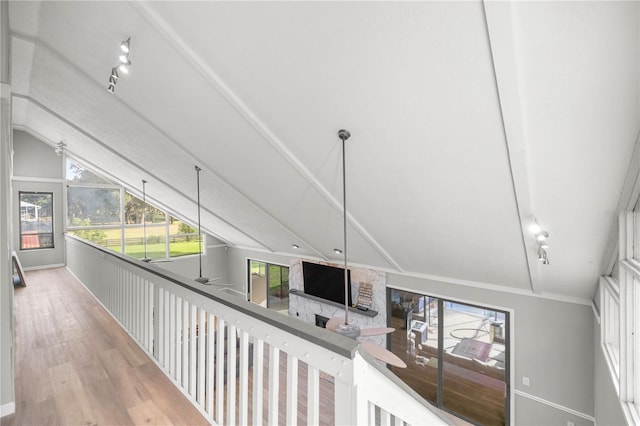 corridor featuring rail lighting, lofted ceiling, and light hardwood / wood-style flooring