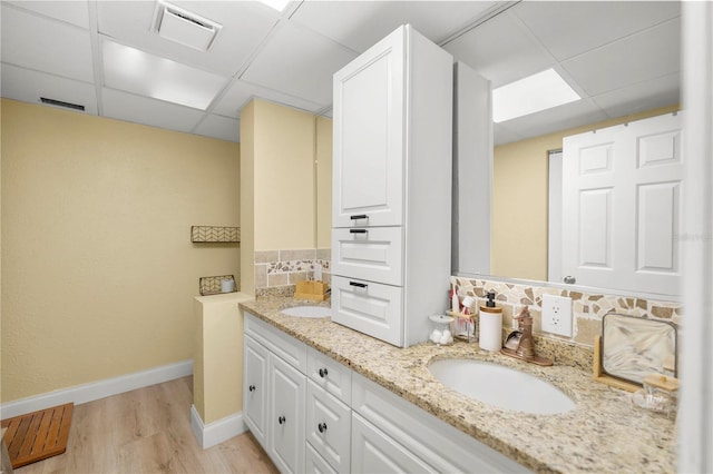 bathroom with hardwood / wood-style flooring, vanity, and a paneled ceiling