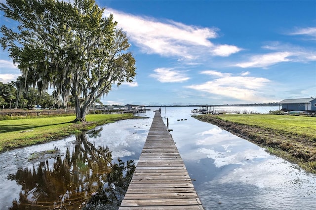 view of dock with a water view and a yard