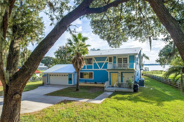 view of front facade with a garage, central AC, a porch, a front lawn, and a water view