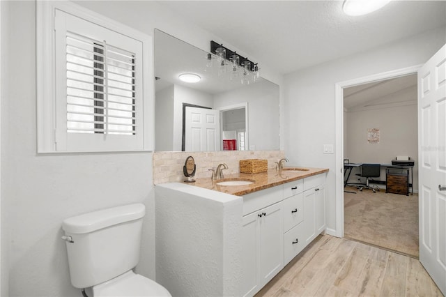 bathroom with wood-type flooring, a textured ceiling, vanity, and toilet