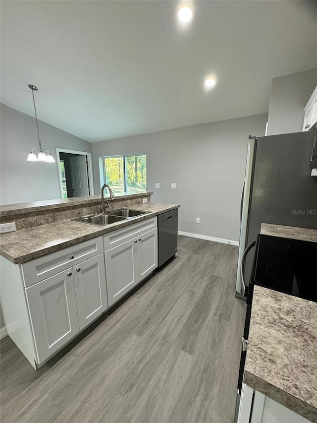 kitchen featuring sink, white cabinetry, decorative light fixtures, vaulted ceiling, and appliances with stainless steel finishes