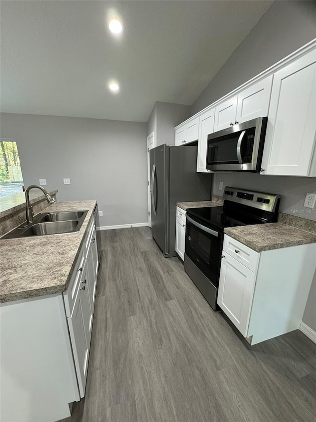 kitchen with hardwood / wood-style flooring, stainless steel appliances, sink, and white cabinets