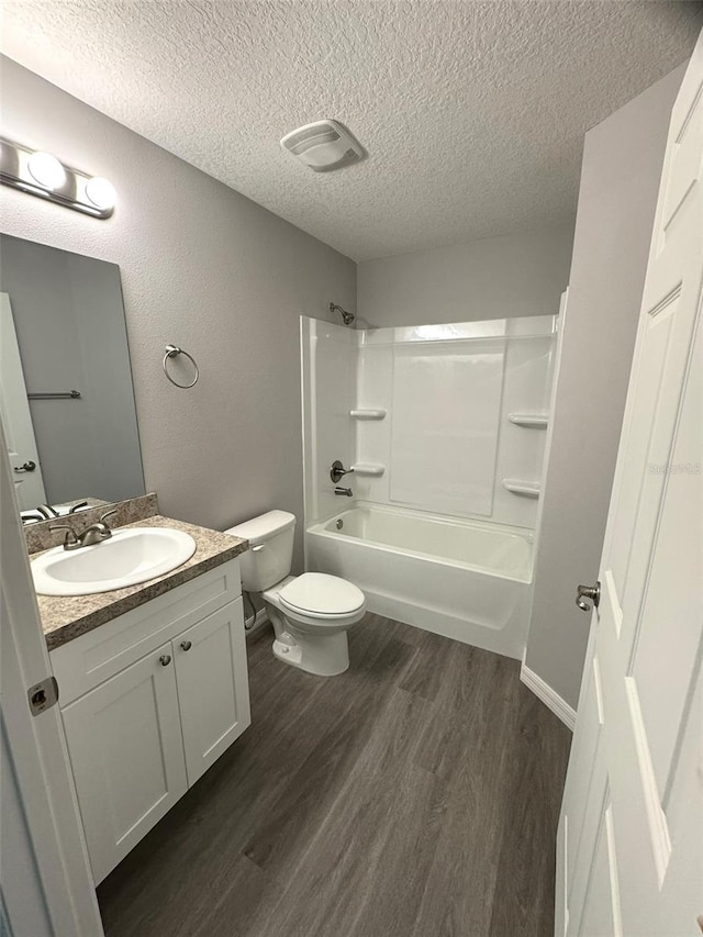 full bathroom featuring shower / washtub combination, wood-type flooring, vanity, toilet, and a textured ceiling