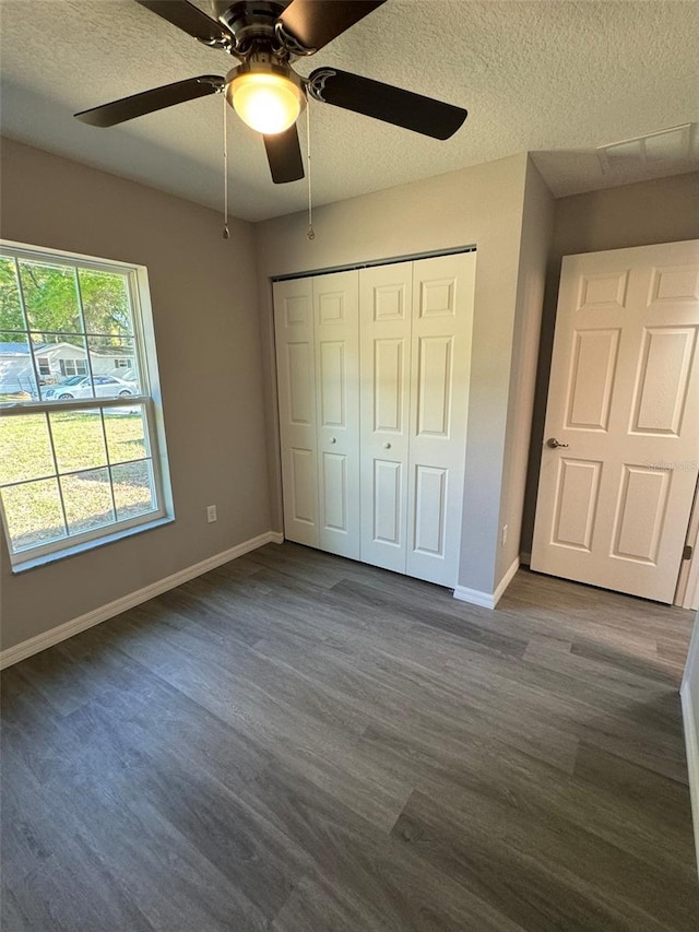 unfurnished bedroom with ceiling fan, a closet, dark hardwood / wood-style floors, and a textured ceiling