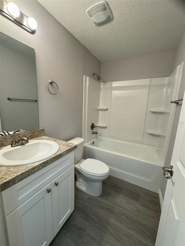 full bathroom featuring toilet, wood-type flooring, tub / shower combination, a textured ceiling, and vanity