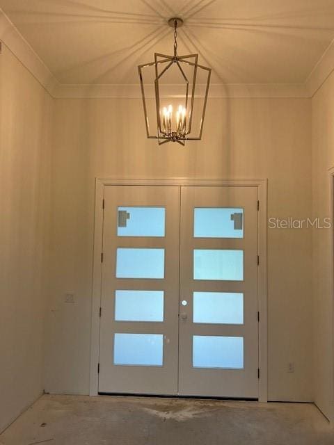 doorway featuring concrete flooring, ornamental molding, a notable chandelier, and french doors