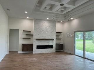 unfurnished living room featuring a large fireplace, light hardwood / wood-style floors, and a towering ceiling