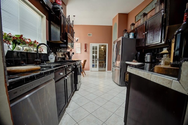 kitchen featuring dark brown cabinets, stainless steel appliances, light tile patterned floors, and sink