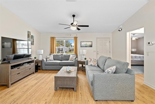 living room featuring ceiling fan, lofted ceiling, light hardwood / wood-style flooring, and a textured ceiling