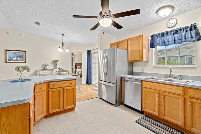 kitchen with pendant lighting, sink, appliances with stainless steel finishes, ceiling fan with notable chandelier, and vaulted ceiling