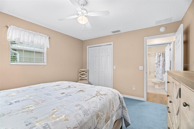 bedroom featuring connected bathroom, a textured ceiling, a closet, ceiling fan, and carpet