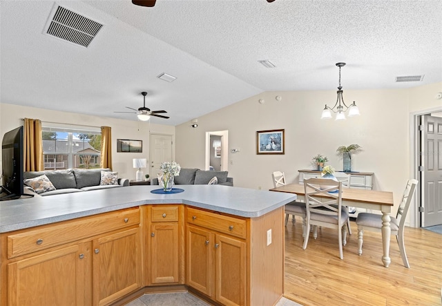 kitchen with vaulted ceiling, pendant lighting, ceiling fan with notable chandelier, a textured ceiling, and light hardwood / wood-style flooring