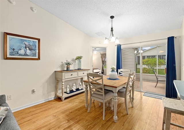 dining room featuring vaulted ceiling, ceiling fan with notable chandelier, a textured ceiling, and light hardwood / wood-style floors