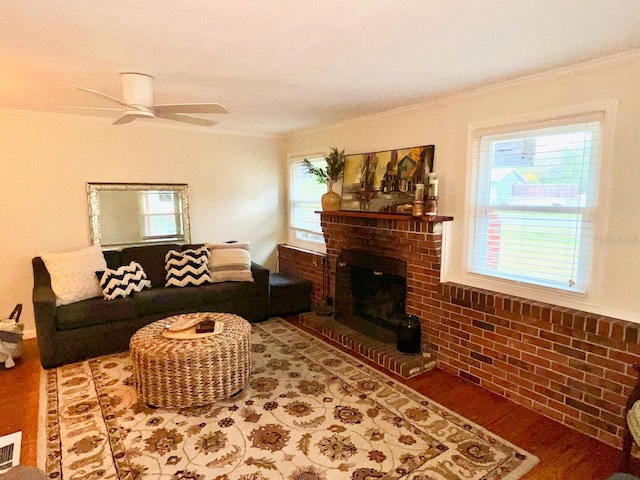 living room featuring hardwood / wood-style floors, ornamental molding, a fireplace, and ceiling fan