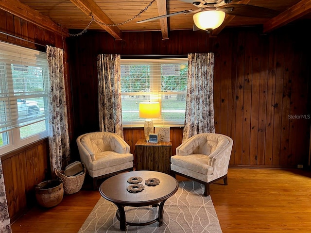 sitting room featuring hardwood / wood-style floors, ceiling fan, beam ceiling, wooden ceiling, and wooden walls