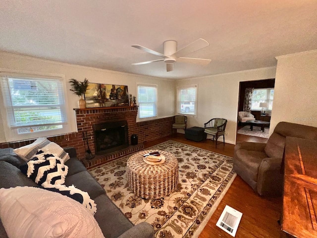 living room featuring ceiling fan, a brick fireplace, dark wood-type flooring, and crown molding