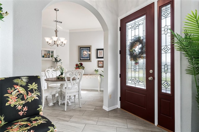 foyer entrance with light tile floors, ornamental molding, and a chandelier