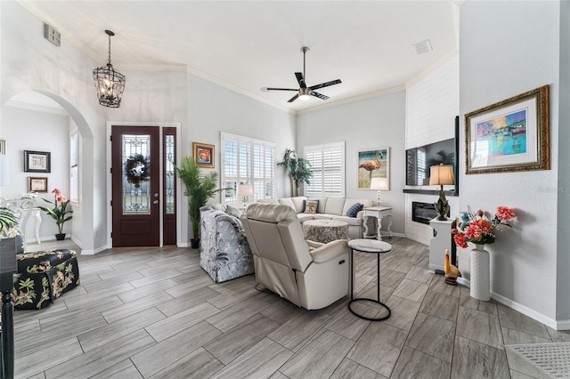 living room featuring ornamental molding and ceiling fan with notable chandelier