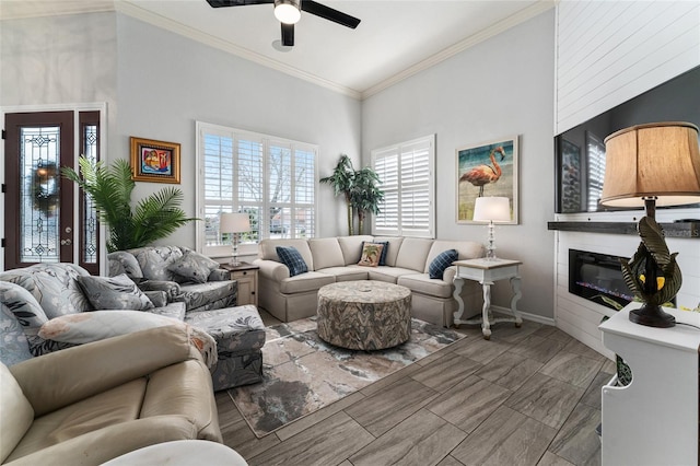 living room with crown molding, ceiling fan, and a towering ceiling