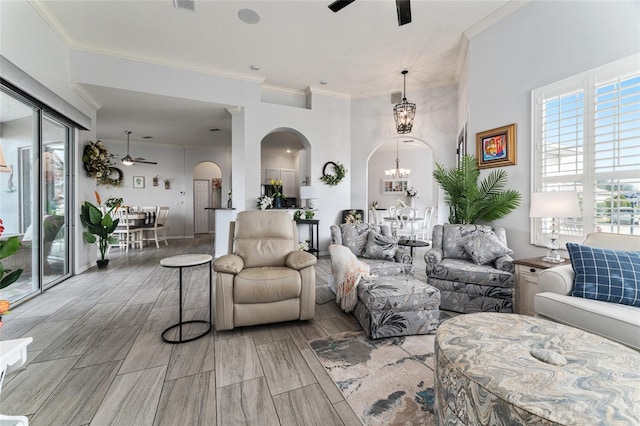 living room featuring light hardwood / wood-style flooring, ceiling fan with notable chandelier, and ornamental molding